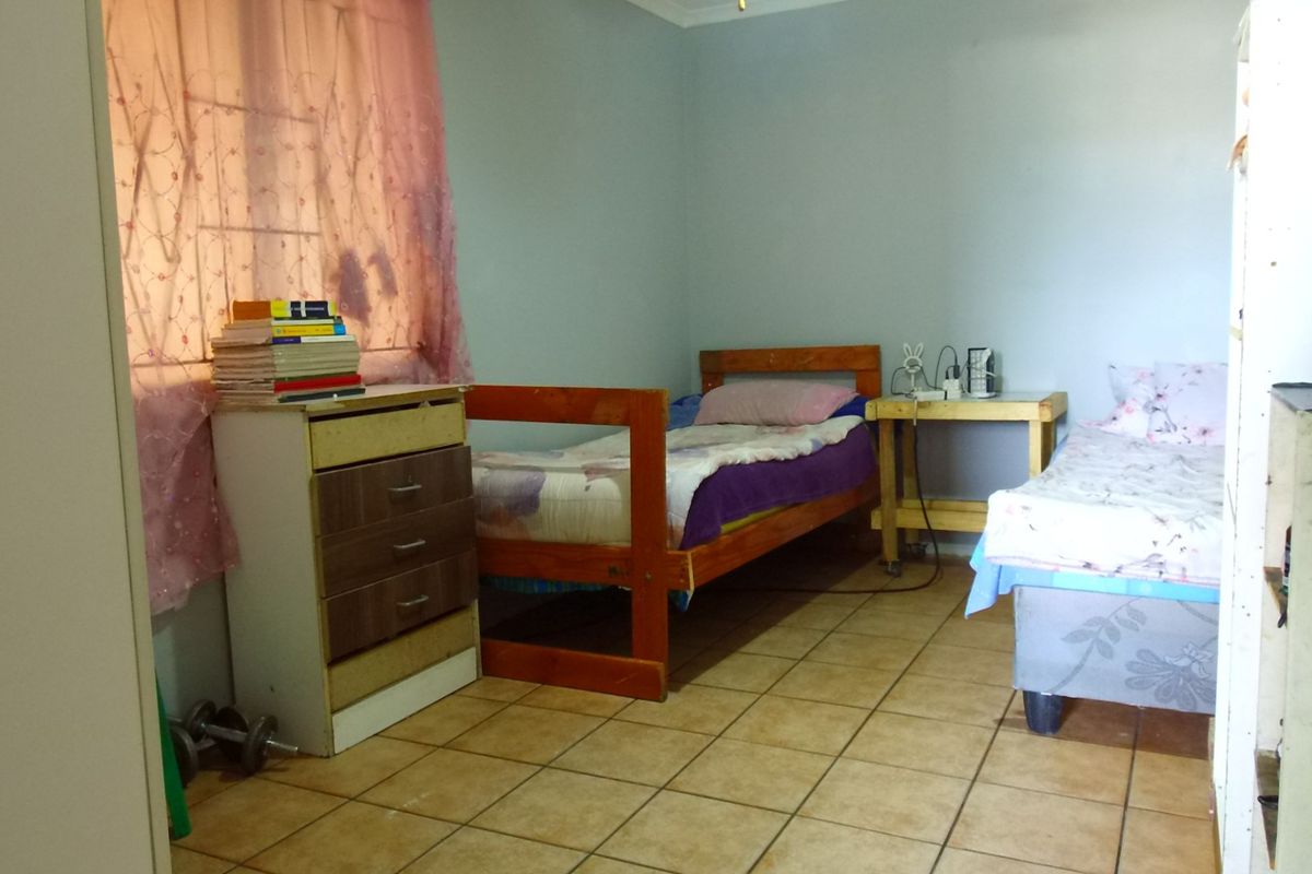 A functional bedroom featuring tiled flooring and built-in storage, offering a practical space that could benefit from cosmetic updates.