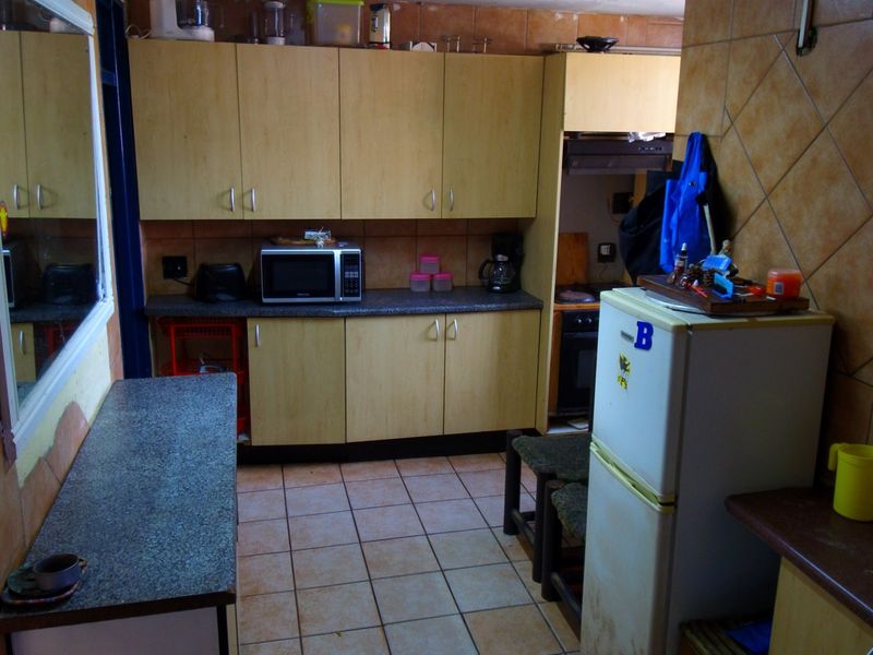 A dated kitchen featuring built-in cabinetry, laminate countertops, and tiled wall splashbacks, offering potential for a modern renovation.