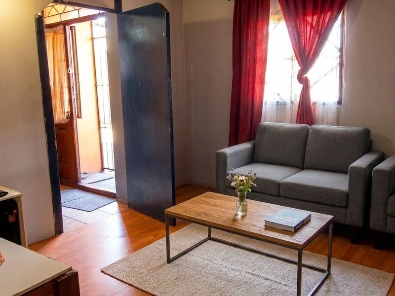 A living room area featuring laminate flooring and direct access to an exterior entrance.
