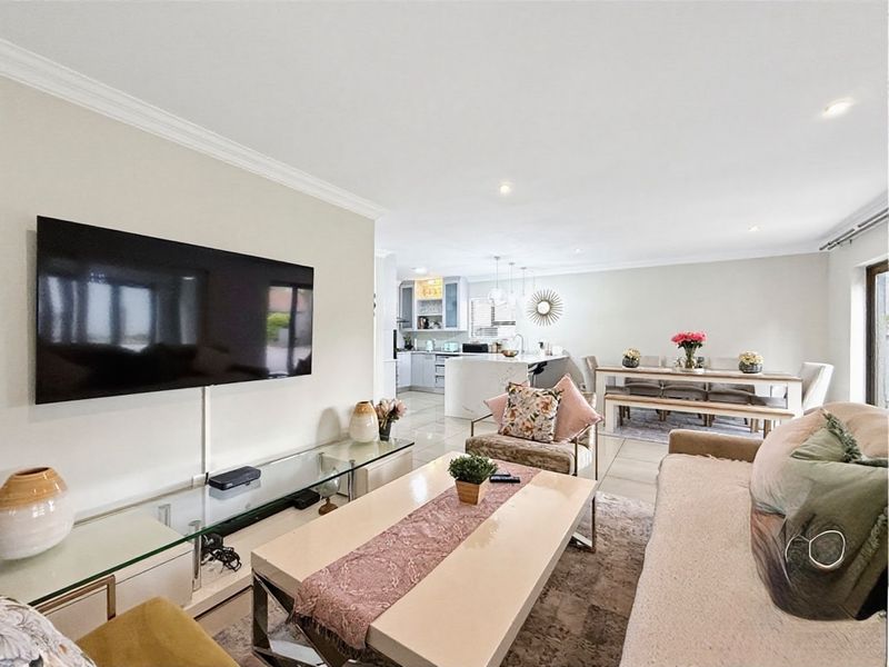 Spacious open-plan living and dining area featuring tiled floors, recessed lighting, and a modern kitchen with a central island.