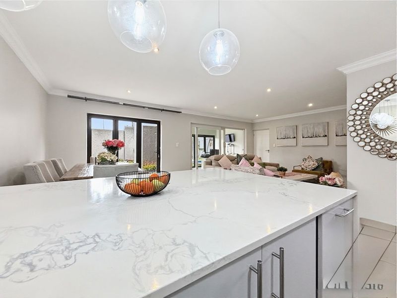 Spacious open-plan living area featuring a modern kitchen island with quartz countertops, recessed lighting, and seamless flow to the dining and lounge spaces.