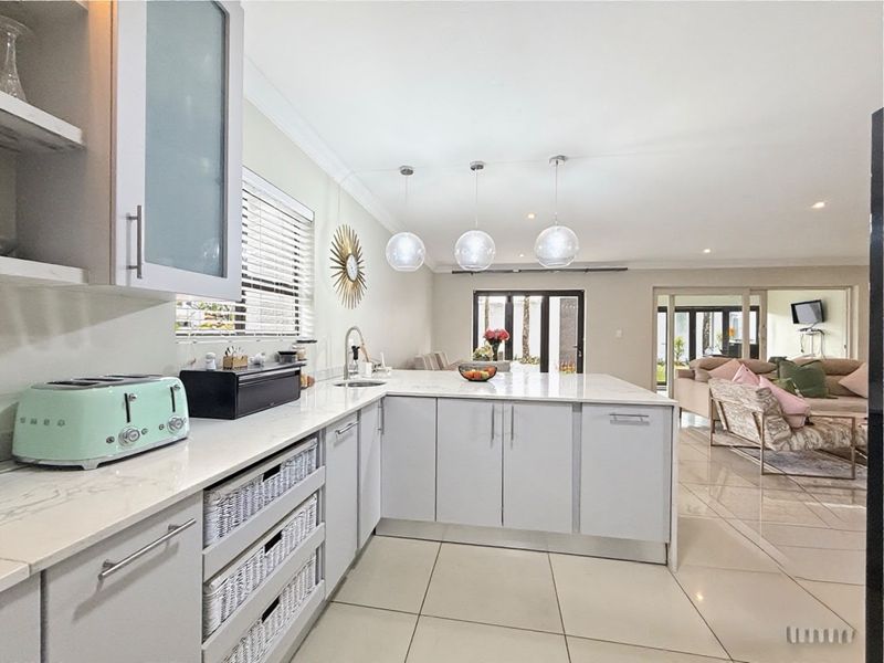 Modern open-plan kitchen featuring a central island with quartz countertops, sleek cabinetry, and pendant lighting, flowing seamlessly into the adjacent living area.