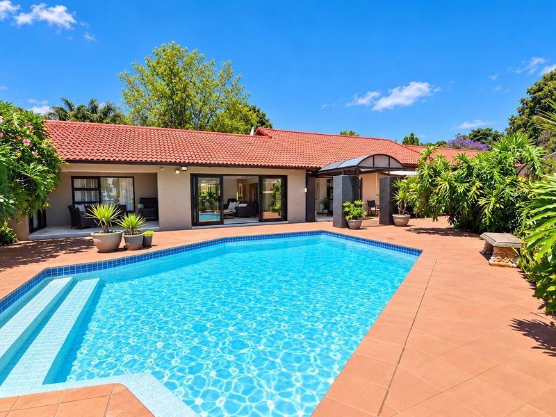 A well-maintained outdoor pool area featuring a tiled patio, swimming pool, and direct access to the home through sliding glass doors.