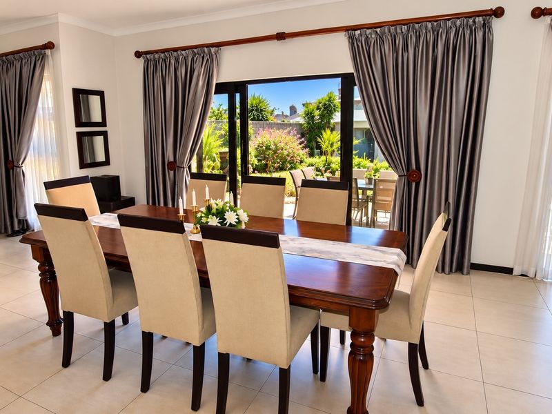 A bright dining room featuring tiled flooring and large sliding glass doors that provide direct access to the outdoor patio and garden area.