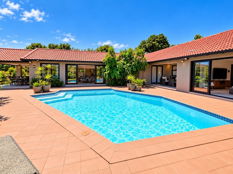 A well-maintained outdoor pool area featuring a tiled surround, integrated patio space, and direct access to the home through large sliding glass doors.