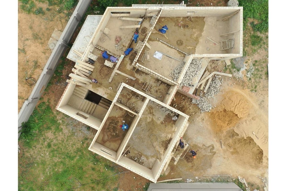 Aerial view of a residential property under construction showing the foundation, block walls, and staircase layout.