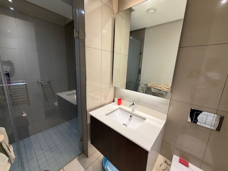 Modern bathroom featuring a wall-mounted vanity with integrated basin, frameless glass shower enclosure, and a wall-hung toilet with a concealed cistern.