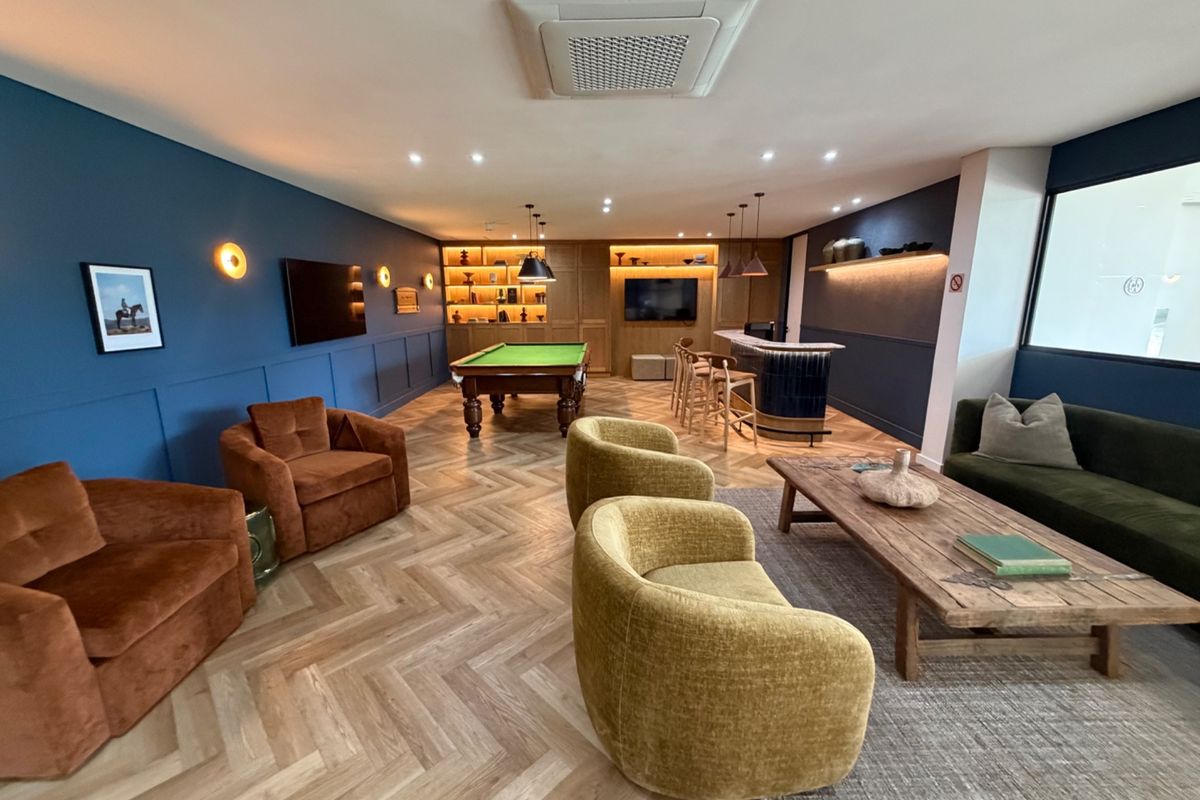 A sophisticated entertainment lounge featuring a built-in bar, pool table, herringbone wood flooring, and elegant wainscoting with integrated lighting.