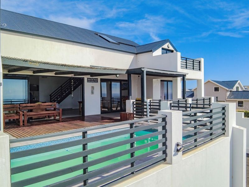 Rear exterior view featuring a swimming pool, timber decking, and a covered patio area with metal balustrades and modern architectural finishes.