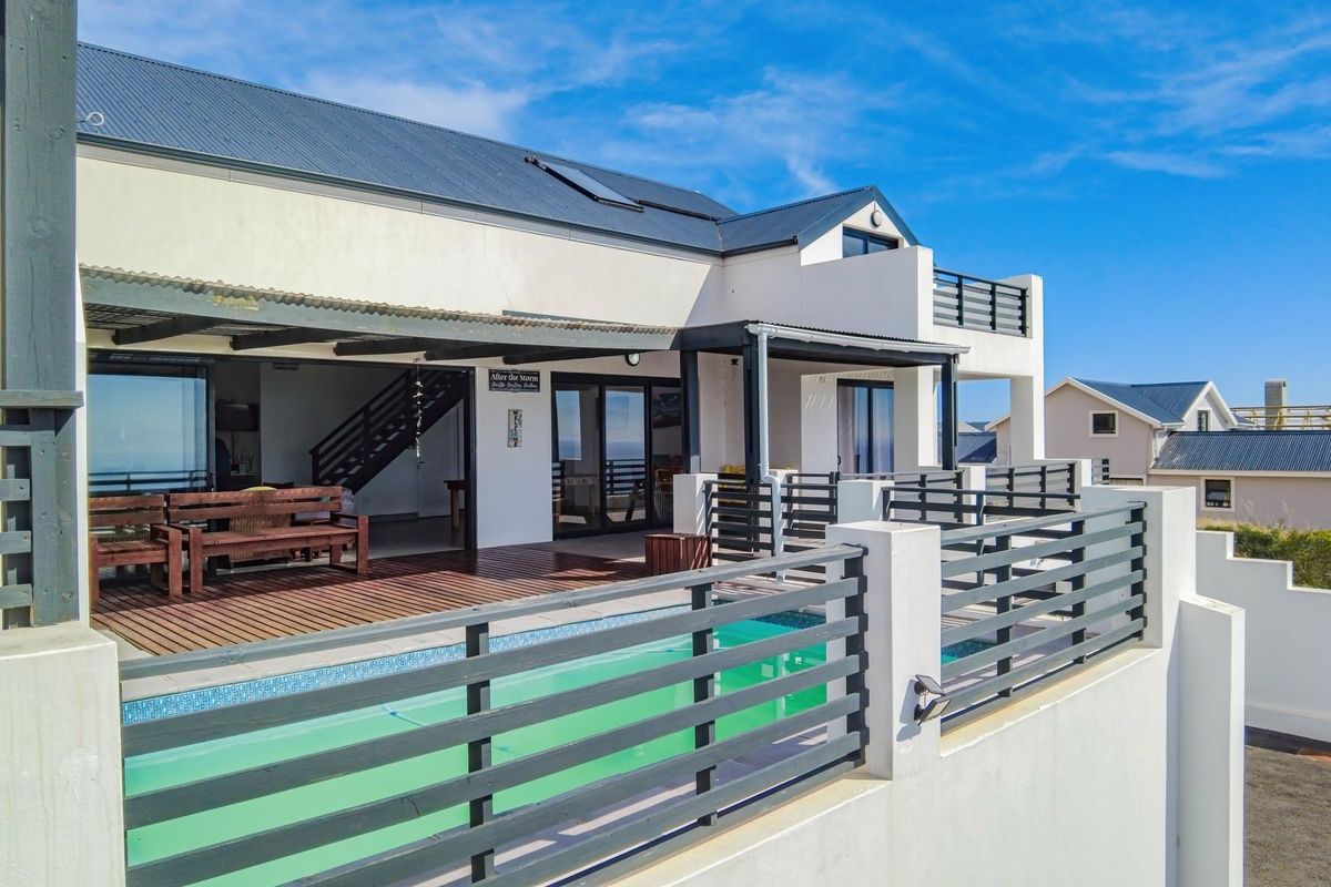 Rear exterior view featuring a swimming pool, timber decking, and a covered patio area with metal balustrades and modern architectural finishes.