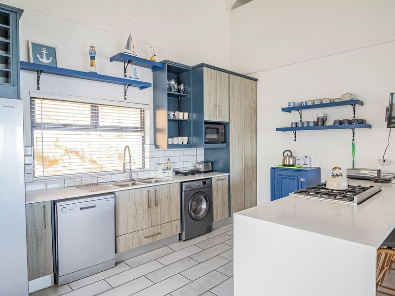 Modern kitchen featuring two-tone cabinetry, a central island with a gas hob, subway tile backsplash, and integrated appliances in a bright, open-plan space.