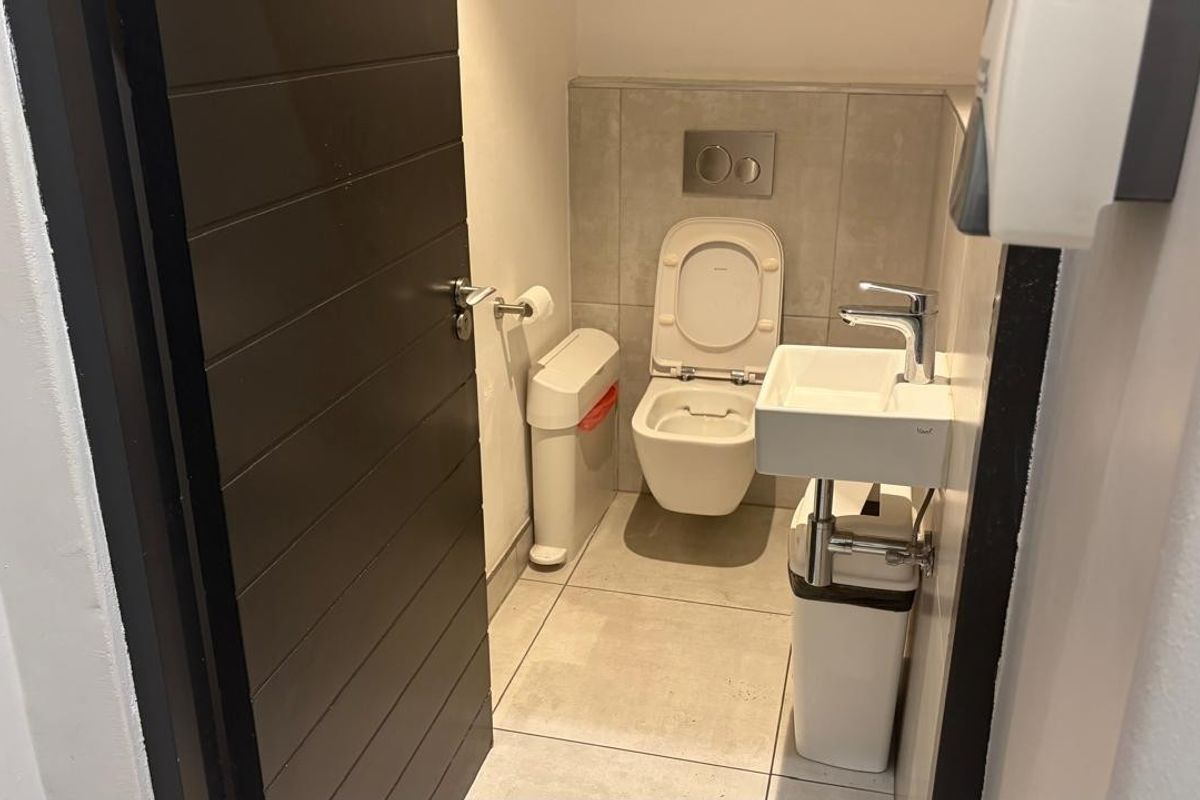 A compact, modern bathroom featuring a wall-mounted toilet with a concealed cistern and a small wall-mounted basin with a chrome mixer tap.