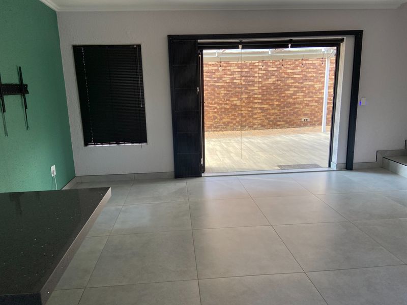 Spacious living area featuring large format floor tiles and seamless access to an outdoor patio through modern sliding stacker doors.