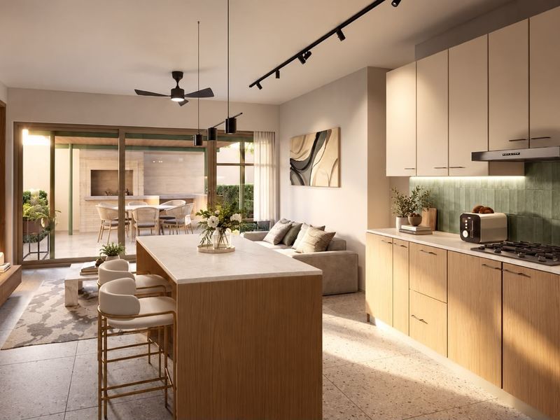 Modern open-plan living area featuring a sleek kitchen with island, high-end finishes, and seamless flow to a covered outdoor patio space.