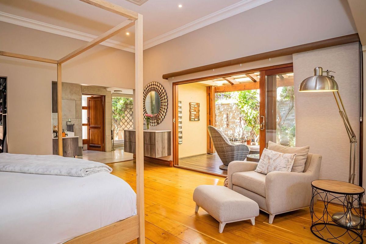 Spacious bedroom featuring warm hardwood flooring, crown molding, and large sliding glass doors that open onto a private patio area.