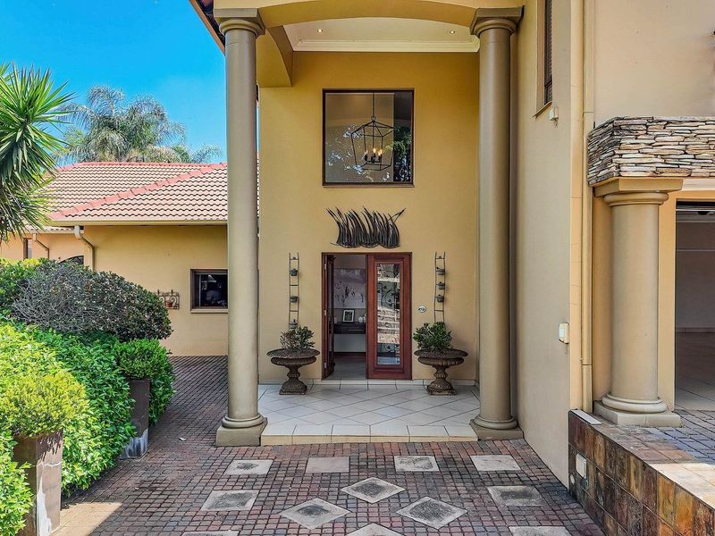 A grand front entrance featuring a covered porch with columns, stone accents, and a paved driveway leading to the main door.
