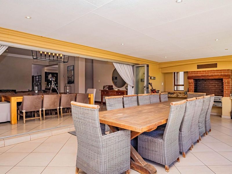 Spacious covered patio featuring tiled flooring, recessed lighting, and a built-in brick fireplace, seamlessly connecting to the indoor living area through large sliding doors.