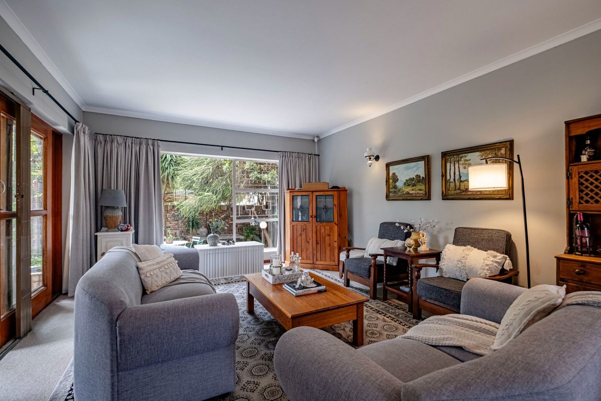 A comfortable living room featuring a large window, sliding glass door access to the exterior, and classic cove cornicing.