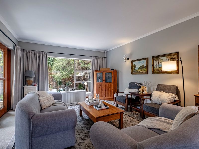 A comfortable living room featuring a large window, sliding glass door access to the exterior, and classic cove cornicing.
