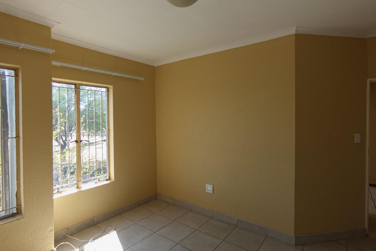 An empty bedroom featuring tiled flooring, coved ceilings, and windows fitted with security bars, offering a blank canvas for personalization.