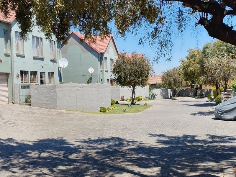 A view of the townhouse complex driveway featuring paved surfaces, garage access, and established residential building facades.