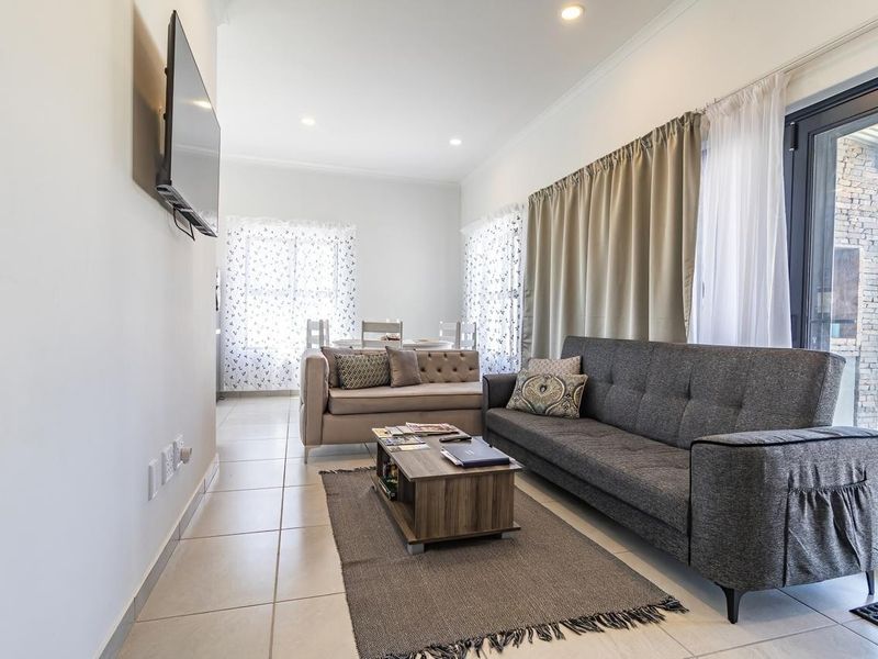 A bright and open living room featuring tiled flooring, recessed downlights, and a large sliding glass door providing access to the outdoor area.