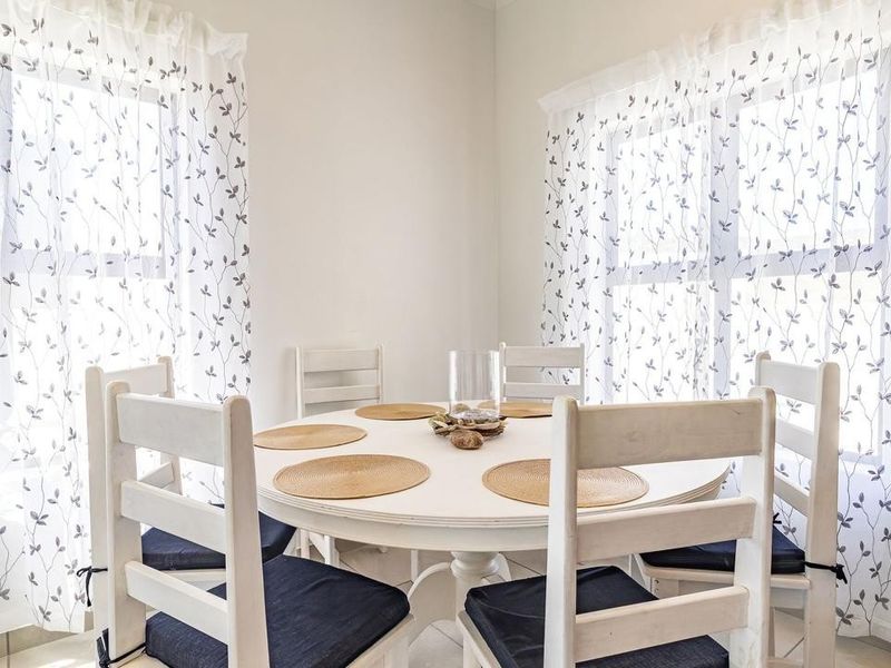 A bright and airy dining area featuring neutral tiled flooring and dual windows that provide ample natural light.