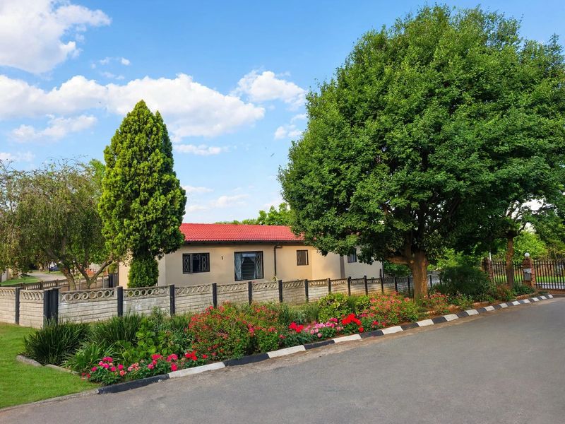 A well-maintained single-story house featuring a red tiled roof, secure window bars, and a neat front garden with a precast boundary wall.