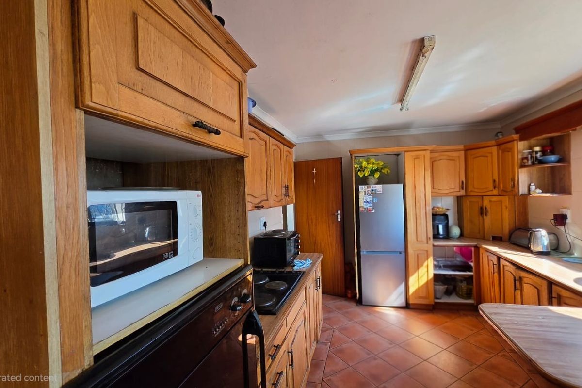A functional kitchen featuring traditional wooden cabinetry, tiled flooring, and built-in cooking appliances, offering a classic layout with potential for modern updates.