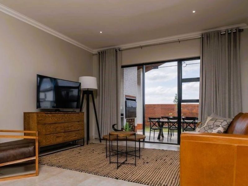 A well-maintained living room featuring recessed lighting, cornicing, and large sliding glass doors that provide seamless access to the outdoor patio area.
