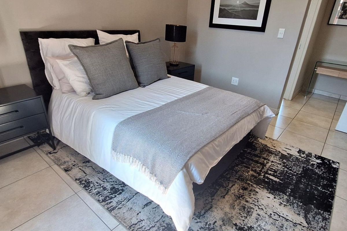 A well-maintained bedroom featuring neutral wall tones, tiled flooring, and built-in storage, offering a clean and functional living space.