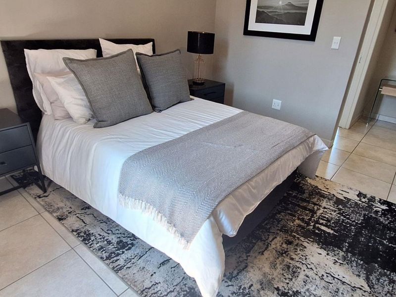 A well-maintained bedroom featuring neutral wall tones, tiled flooring, and built-in storage, offering a clean and functional living space.