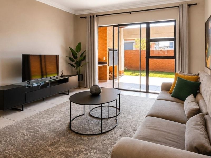 A well-maintained living room featuring tiled flooring and a large sliding glass door that provides seamless access to the outdoor patio area.