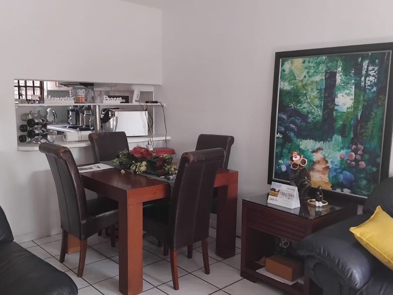 Open plan living and dining area featuring tiled flooring and a convenient pass-through window connecting to the kitchen space.