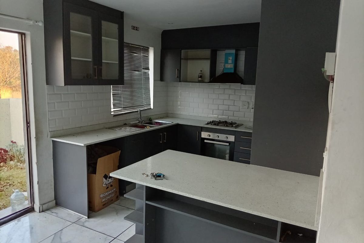 Modern kitchen featuring dark cabinetry, stone countertops, subway tile backsplash, integrated gas hob, oven, and a functional breakfast bar area.