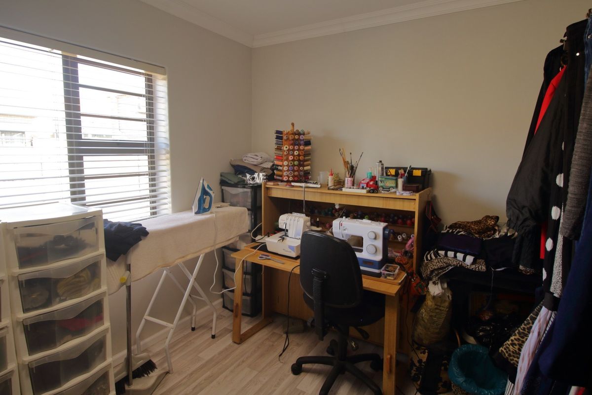 A functional bedroom space featuring laminate flooring and venetian blinds, currently utilized as a hobby and craft room.