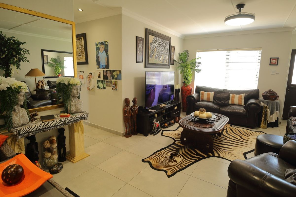 A well-maintained living room featuring neutral tiled flooring, recessed ceiling lighting, and a ceiling fan, providing a comfortable and functional living space.