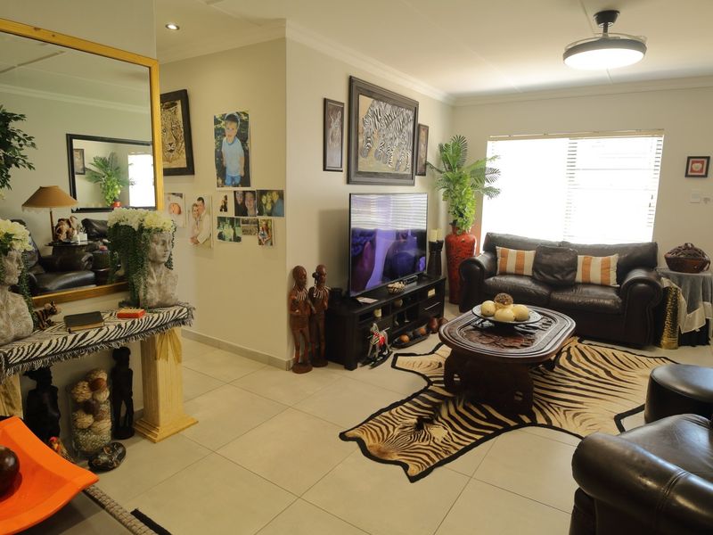 A well-maintained living room featuring neutral tiled flooring, recessed ceiling lighting, and a ceiling fan, providing a comfortable and functional living space.