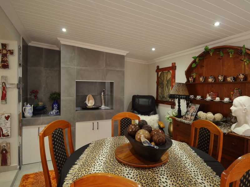 Open plan dining area featuring a modern tiled built-in fireplace, recessed downlights, and tongue and groove ceiling finishes.
