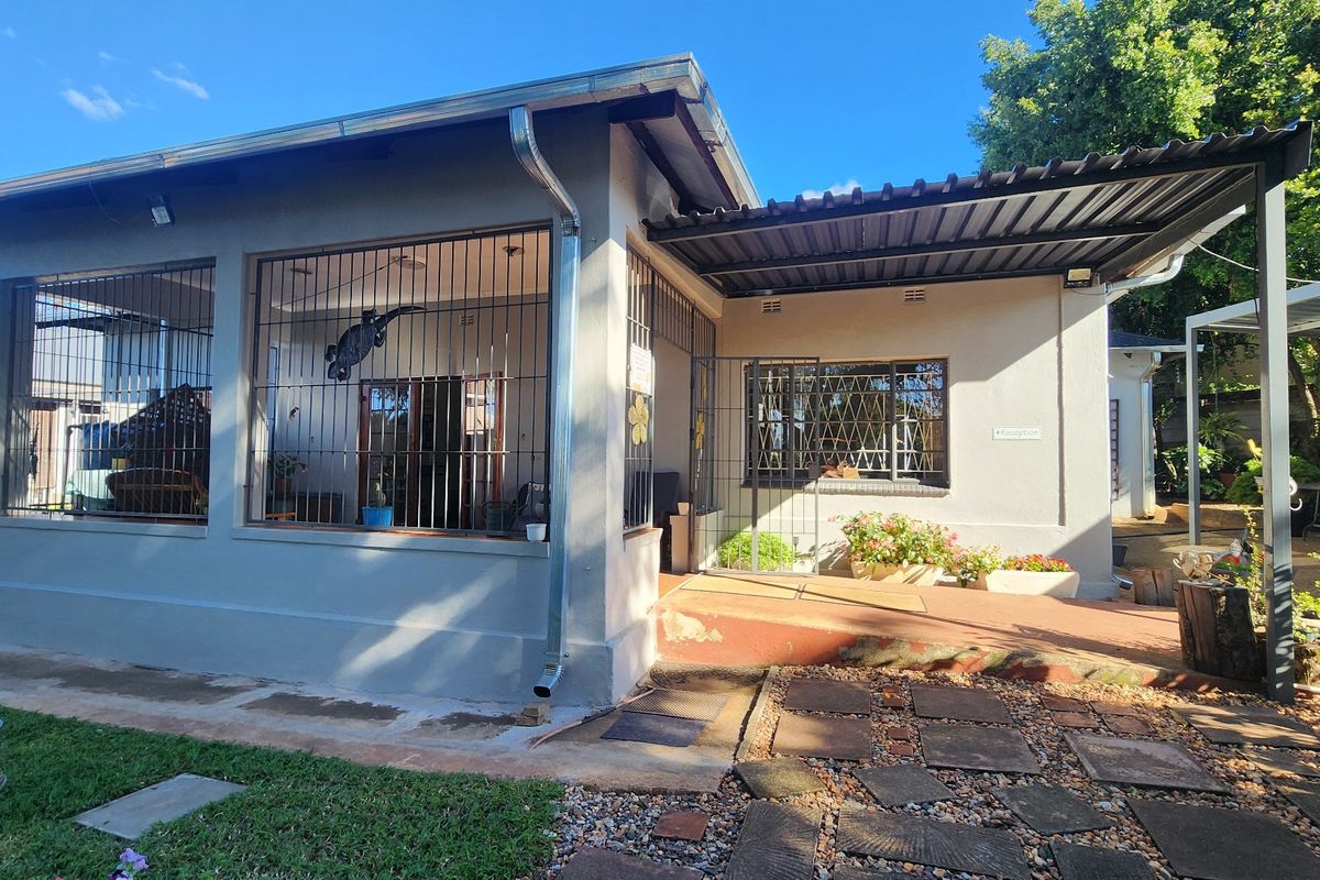 Rear exterior view of the house featuring a covered patio area, security bars on windows, and a paved walkway leading to the entrance.