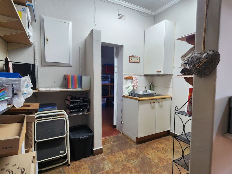 A functional scullery area featuring built-in cabinetry, a stainless steel sink, and tiled flooring, providing additional utility and storage space.