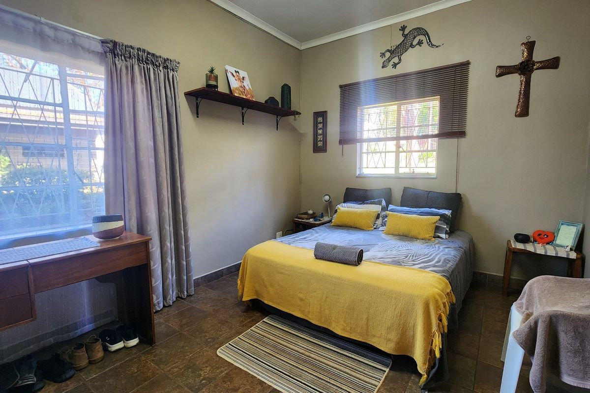 A functional bedroom featuring tiled flooring and windows fitted with security bars, providing a practical and comfortable living space.