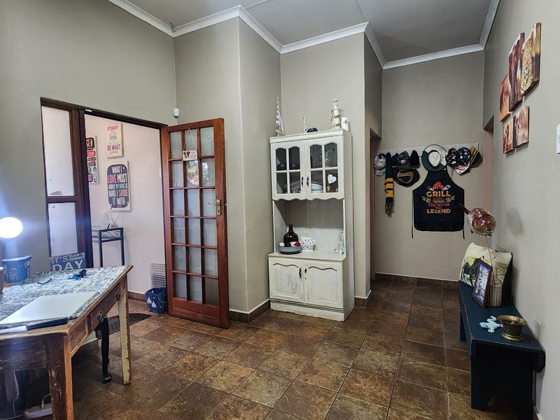 A functional hallway area featuring durable tiled flooring and a classic timber-framed glass door leading to an adjacent room.