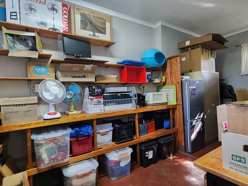 A functional utility or storage room featuring extensive built-in timber shelving and durable concrete flooring, providing ample space for organization and storage needs.