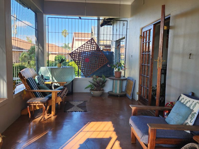 A covered patio area featuring concrete flooring, security bars, and access to the interior through classic french doors.