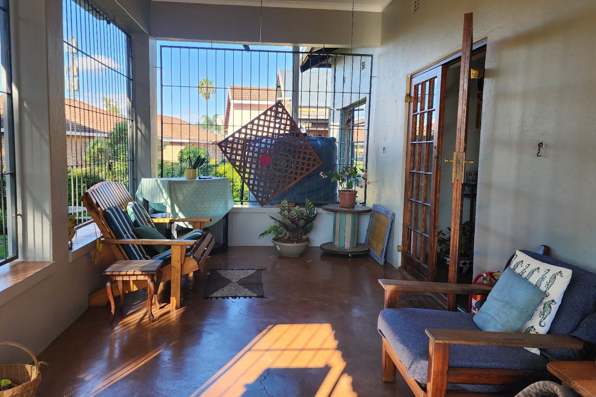 A covered patio area featuring concrete flooring, security bars, and access to the interior through classic french doors.