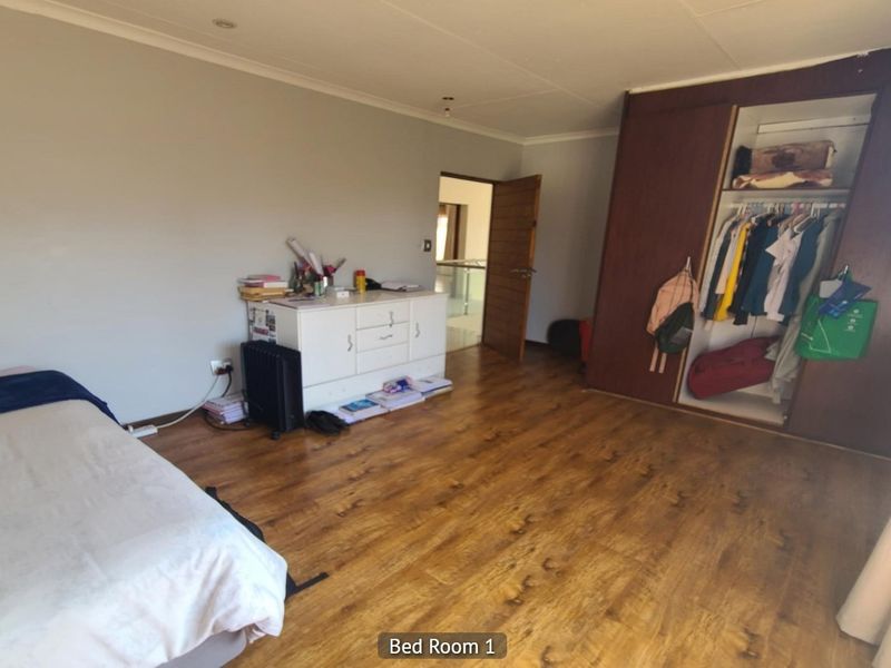 Spacious bedroom featuring laminate flooring, recessed ceiling lighting, and a large built-in wardrobe with sliding doors.
