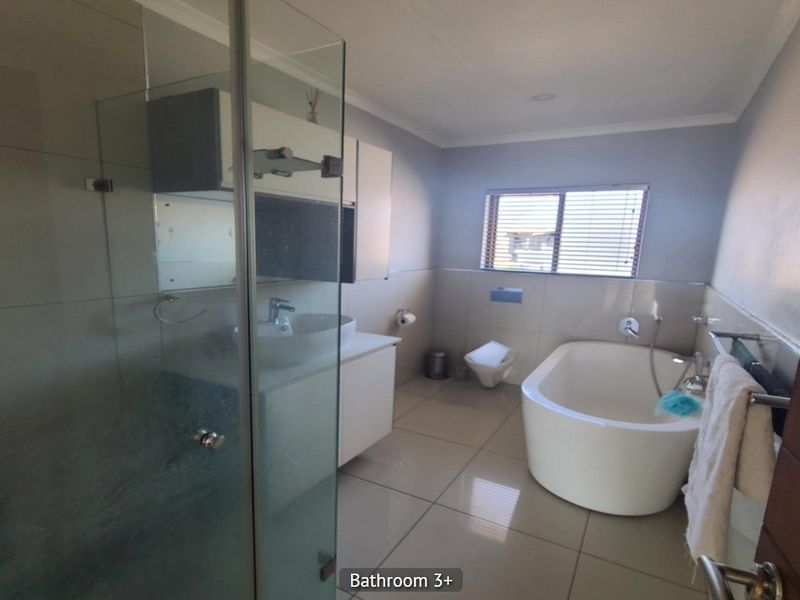 Modern bathroom featuring a glass shower enclosure, a sleek freestanding bathtub, a wall-mounted toilet, and a vanity with a basin.