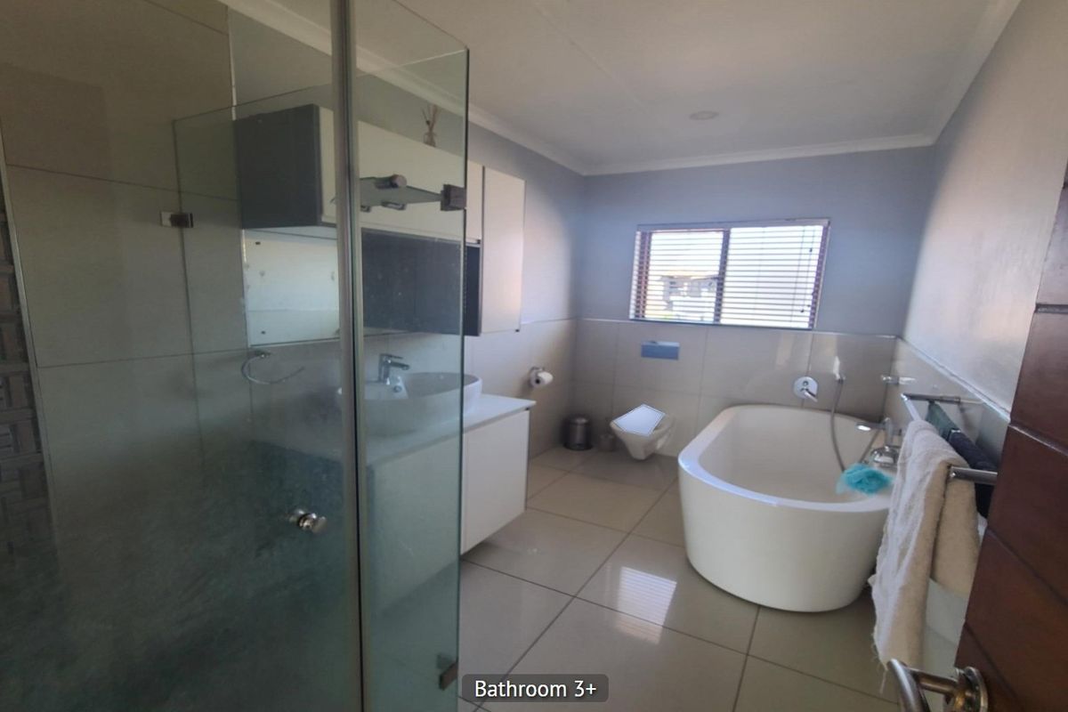 Modern bathroom featuring a glass shower enclosure, a sleek freestanding bathtub, a wall-mounted toilet, and a vanity with a basin.