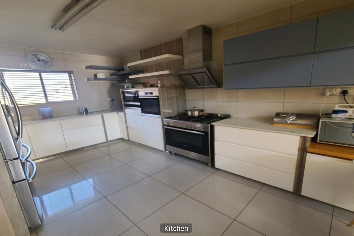 Modern kitchen featuring sleek white and grey cabinetry, stainless steel gas stove with extractor, tiled flooring, and ample counter space.
